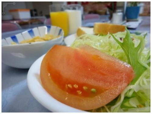 a white plate with a salad and a tomato on it at Sun Hotel Kokubu - Vacation STAY 62468v in Kirishima