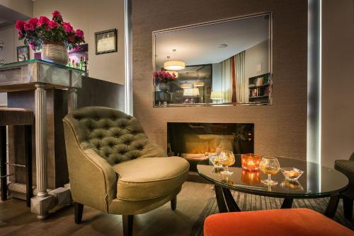 a living room with a chair and a table and a fireplace at Hôtel Harvey in Paris