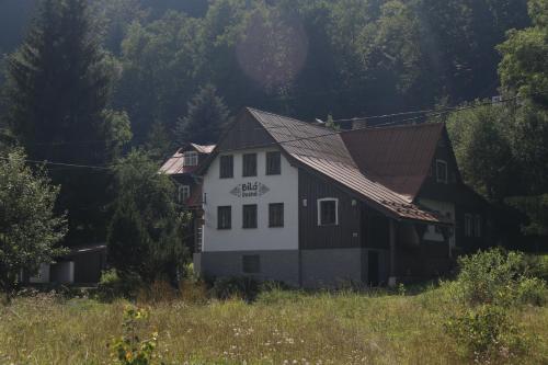 a white and black house in a field at Chalupa Bílá Desná in Jablonec nad Nisou