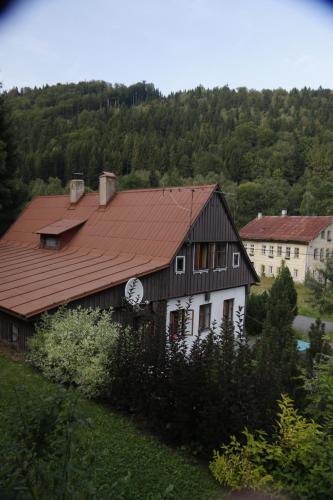 a large house with a red roof in a field at Chalupa Bílá Desná in Jablonec nad Nisou