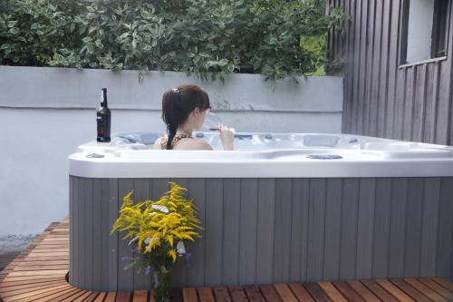 a woman sitting in a bath tub with a bottle of wine at Chalupa Bílá Desná in Jablonec nad Nisou