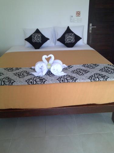 dos cisnes están sentados en una cama en Kubu Sunset Guest House, en Nusa Lembongan
