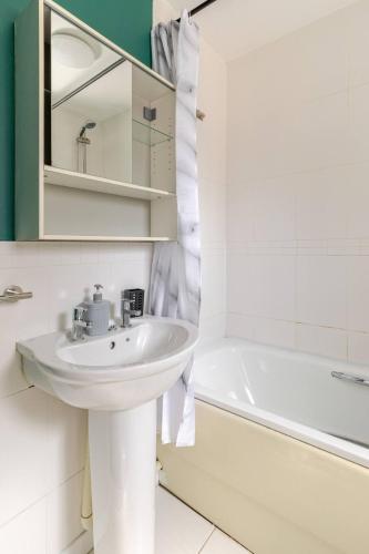 a white bathroom with a sink and a bath tub at Lovely Apartment with Garden & Parking in Milton Keynes