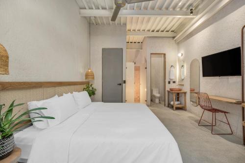 a bedroom with a large white bed and a chair at Botánica Casa Hotel Manila by HOUSY HOST in Medellín