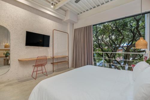 a bedroom with a bed and a large window at Botánica Casa Hotel Manila by HOUSY HOST in Medellín