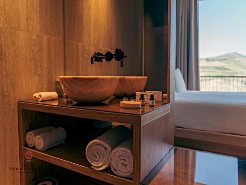 a bathroom with a bowl sink and towels on a shelf at Barrilario Douro Wine Hotel e Spa - Quinta São Jose do Barrilario in Armamar