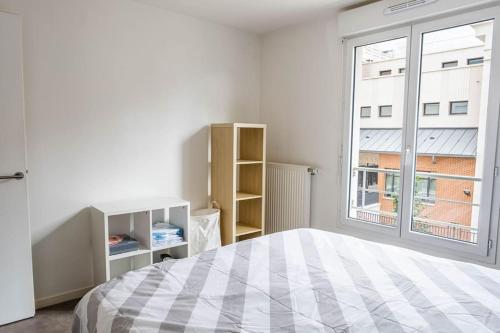 une chambre avec un lit et une grande fenêtre dans l'établissement L'escapade confortable, au Blanc-Mesnil