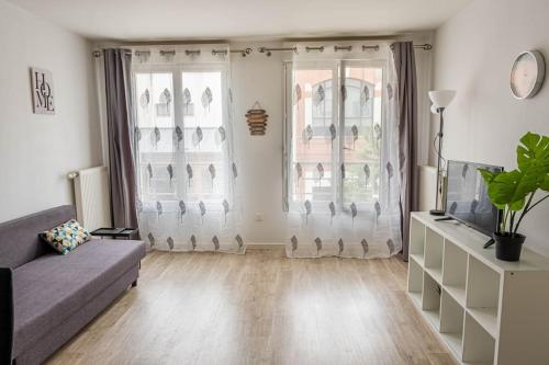 ein Wohnzimmer mit einer Couch und zwei Fenstern in der Unterkunft L'escapade confortable in Le Blanc-Mesnil