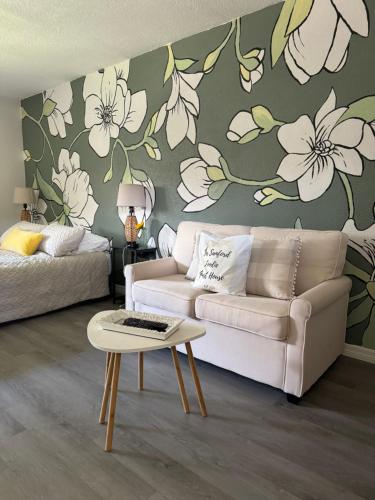 a living room with a couch and flowers on the wall at The Sanford Foodie Guest House in Sanford