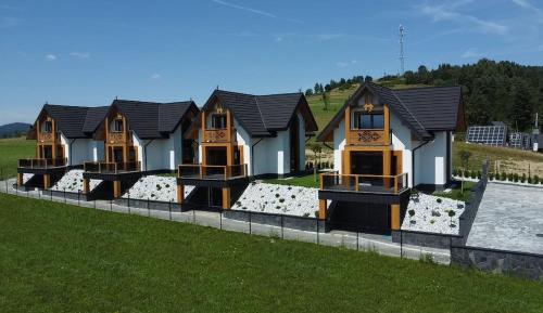 a row of houses sitting on top of a field at Porębiańska Osada Resort & Spa in Szlembark
