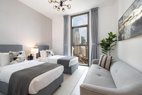 a bedroom with two beds and a couch and a window at High-Rise Chic, Burj Crown, Opera Boulevard View, by Dubai Mall in Dubai