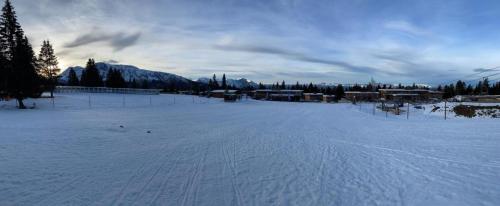 a snow covered field with trees and buildings in the distance at Pied de piste in Chamrousse