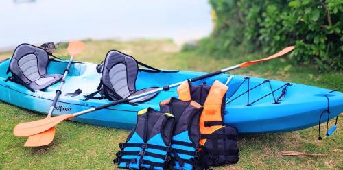 a blue kayak sitting on the grass with two paddles at Beach Front Queen's Castle - Kid friendly, Holiday like Royalty in Ban Ao Makham
