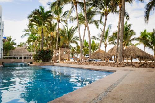 a swimming pool at a resort with palm trees at Hotel Villa Varadero in Nuevo Vallarta 