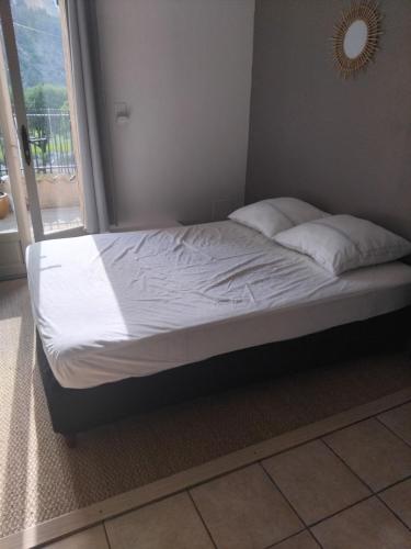 un letto con lenzuola e cuscini bianchi accanto a una finestra di 10 mn Buis les Baronnies a Plaisians