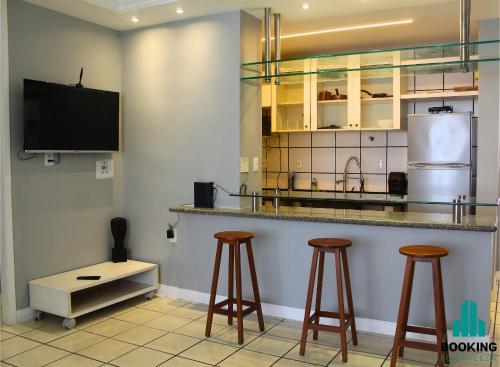 a kitchen with a bar with stools and a tv at Estoril Praia de Iracema in Fortaleza