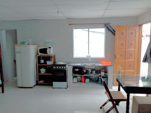 a kitchen with a stove and a refrigerator and a table at Chalé Ubatuba pertinho do mar in Ubatuba