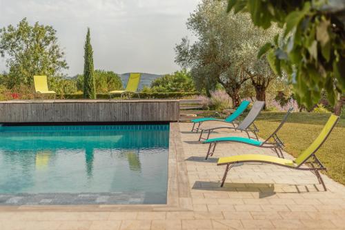 a group of chairs sitting next to a swimming pool at La Villa Bleue, Luxe, Piscine et Spa in Capdenac