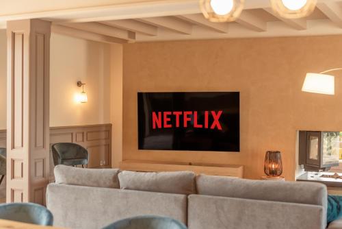 a living room with a couch and a netflix sign on the wall at La Villa Bleue, Luxe, Piscine et Spa in Capdenac