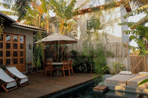 a patio with a table and chairs and an umbrella at Casa Teçá in Guriú