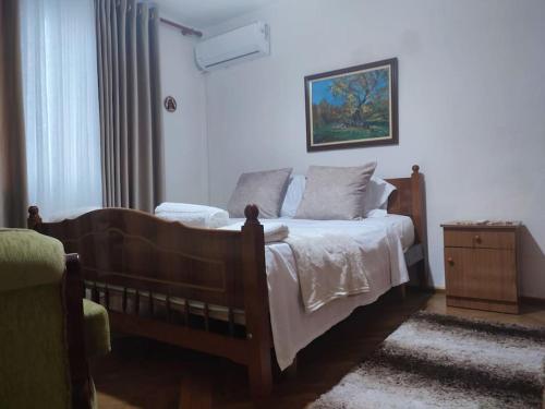 a bedroom with a wooden bed and a dresser and a window at Norga Apartments Shkoder in Shkodër