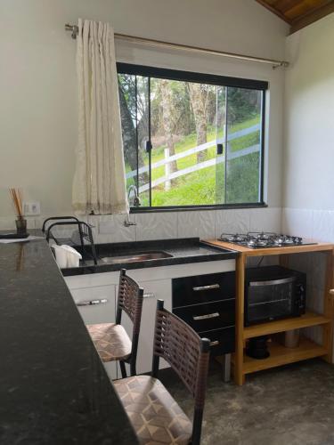 a kitchen with a sink and a window in it at Chalé pedra branca in Dias