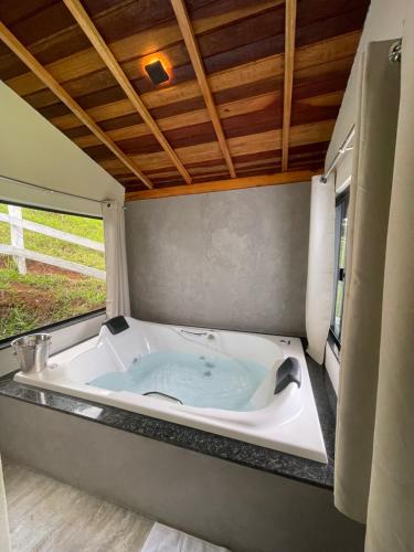 a bath tub in a room with a window at Chalé pedra branca in Dias