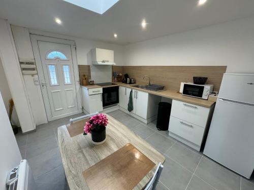 une cuisine avec une table et un réfrigérateur blanc dans l'établissement Le Paisible, à Pontcarré