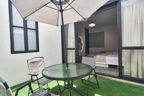 a table and chairs with an umbrella and a bedroom at Aura Hotel B&B in Guadalajara