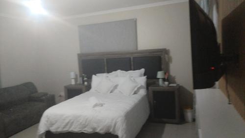 a bedroom with a bed with white sheets and pillows at Green valley in Amanzimtoti