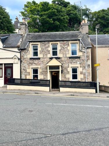 an old stone house on the side of a street at Criss Cross Cottage in Inverness