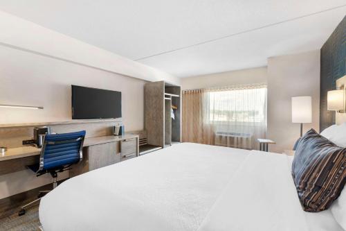 a hotel room with a large bed and a tv at Best Western Plus Landmark Inn in Laconia