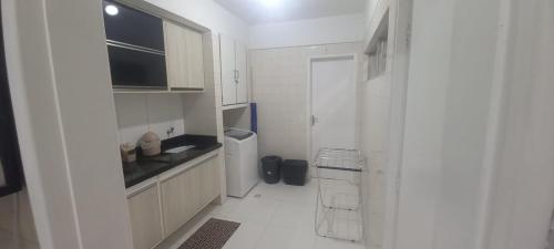 a white kitchen with white cabinets and a sink at Beira Mar ap maceió in Maceió