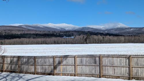 a fence in front of a snow covered field at Charming Stowe Retreat with Mountain Views home in Stowe