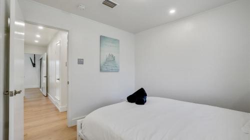 a white bedroom with a black cat sitting on a bed at Holiday 4BR 2BA Home with Pool, Hot Tub, Fire Pit in Irving