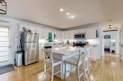 a kitchen with white cabinets and a kitchen island with bar stools at Bird Street Breeze in Oak Bluffs