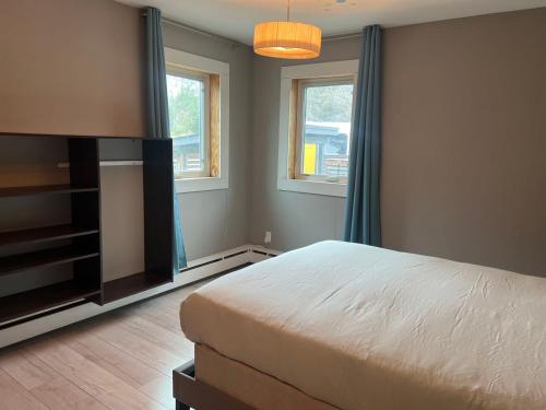 a bedroom with a bed and a tv and two windows at Little Holiday Home in Yellowknife