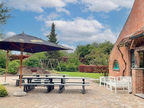 a picnic table and an umbrella next to a brick building at Alverwege in Baerle Heide