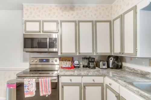 a kitchen with white cabinets and a stove and microwave at Cozy Waycross House with Yard and Screened Patio! in Waycross