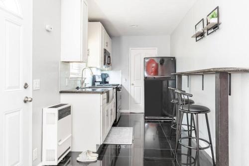 a kitchen with white cabinets and a black refrigerator at Chic Victorian Oasis - Oakland Heart in Oakland