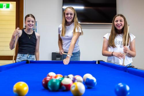 three girls standing next to a pool table at Discovery Parks - West Beach Parks in Adelaide