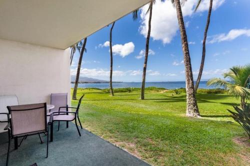 a patio with a table and chairs and palm trees at Sugar Beach Resort, #130 condo in Kihei