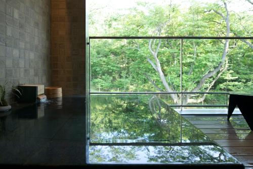 a glass room with a view of a tree at ライムリゾート箱根 in Sengokuhara