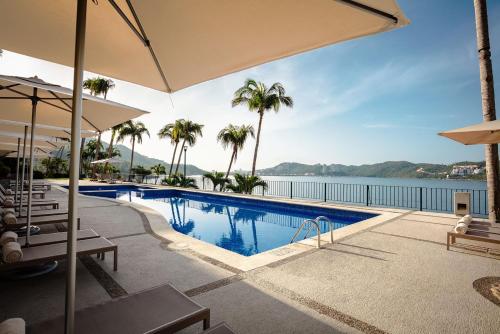 a swimming pool with a view of the water and palm trees at Camino Real Acapulco Diamante in Acapulco