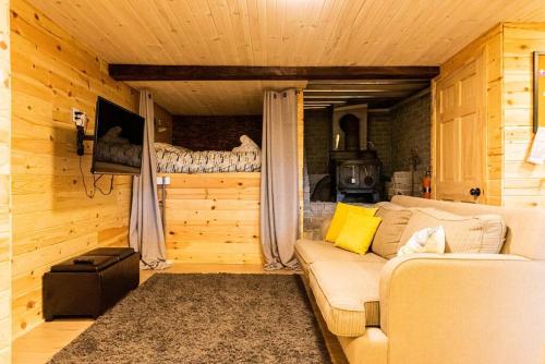 ein Wohnzimmer mit Sofa und Bett in der Unterkunft Le Paresseux - Chalet rustique québécois avec foyer, vue sur le lac et sentiers de randonnée in Saint Come