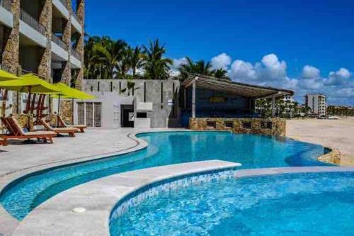 a swimming pool at a resort with chairs and umbrellas at Unique BEACH FRONT condo with concierge in San José del Cabo