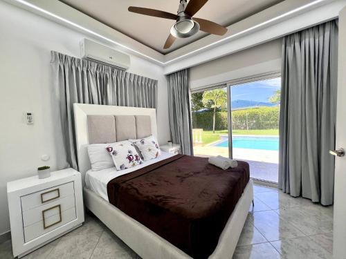 a bedroom with a bed with a ceiling fan and a window at Casa Linda 756 - 5br Modern Villa In Sosua in Sosúa
