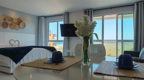 Una sala de estar con una mesa con un jarrón de flores. en Flat Mandai Praia do Forte, en Cabo Frío