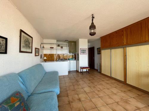 un salon avec un canapé bleu et une cuisine dans l'établissement Studio face à la mer avec terrasse et parking - FR-1-309-44, à Banyuls-sur-Mer