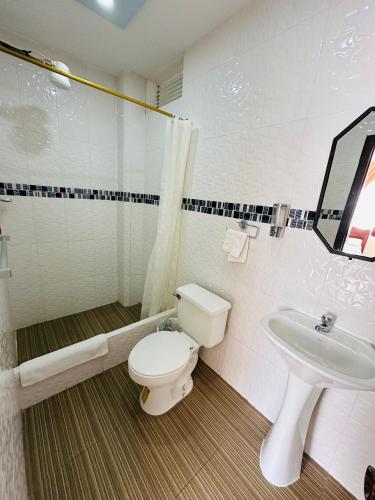 a bathroom with a toilet and a sink at Hotel La Liria in Macas